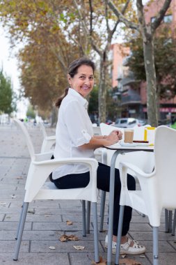 Kafede masada sokakta oturan güzel olgun kadın. 