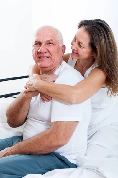 Mature man and woman on   bed in   bedroom.