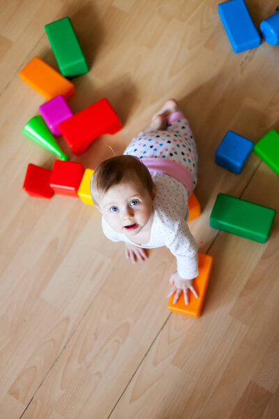  baby playing with plastic cubes on   floor in   room. 