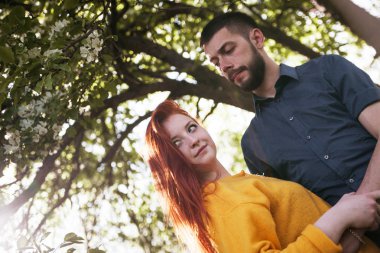 Bahar bahçesinde yürüyen genç bir çift. 