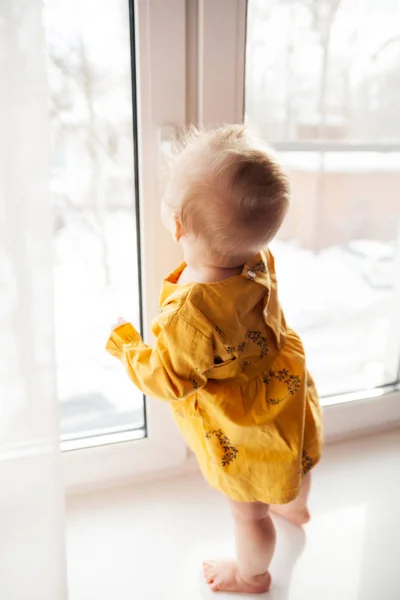 Kleine baby in gevaarlijke positie bij het raam. — Stockfoto