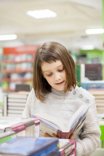 Мила дівчина читає книги в магазині — стокове фото