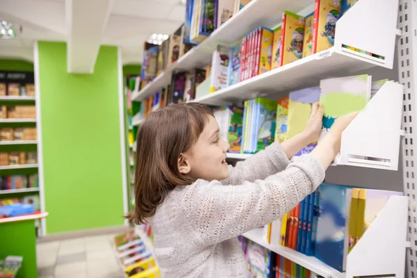 Девушка выбирает книги в книжном магазине — стоковое фото