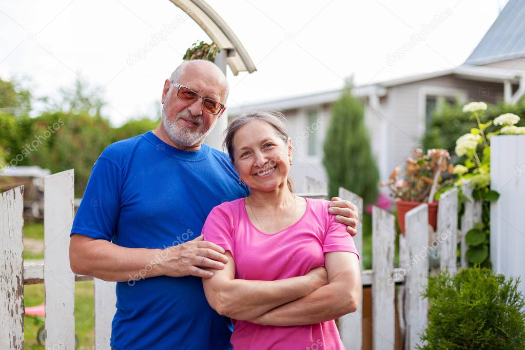  Mature couple at wicket gate of   village cottage