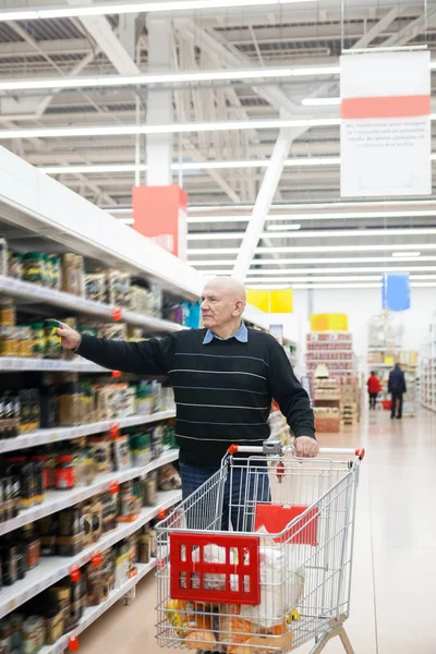 elderly man with   trolley in   supermarket between