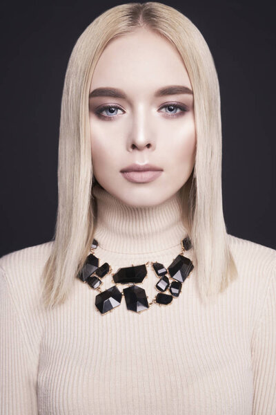 Beautiful young blonde with classic makeup and modern jewelry