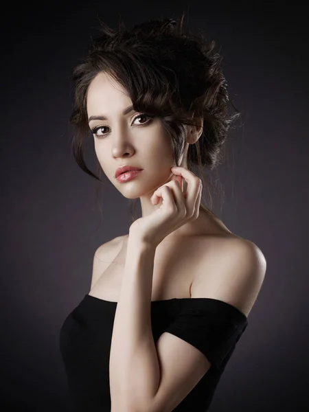 Mulher bonita com penteado elegante no fundo preto — Fotografia de Stock