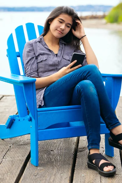 Biracial Teen Ragazza Seduta Sulla Sedia Adirondack Blu Accanto Lago — Foto Stock