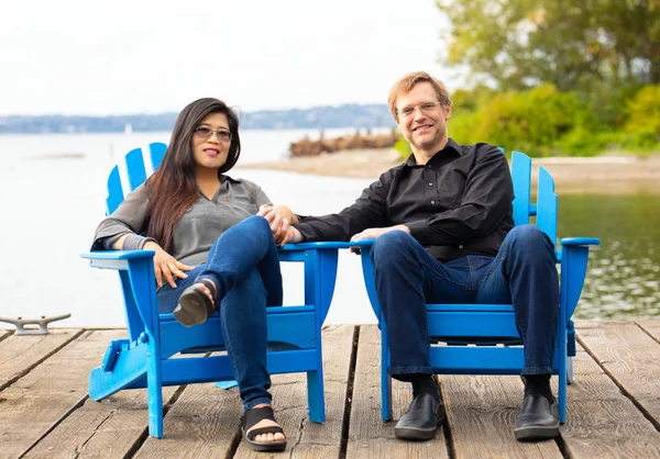 Çok Irklı Çift Beyaz Adam Mavi Adirondack Sandalye Ahşap Iskele — Stok fotoğraf