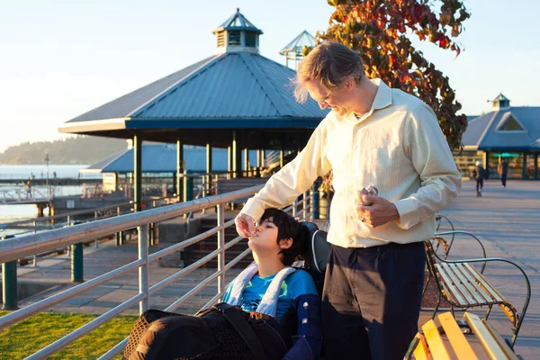 Caucasian Father Forties Feeding Biracial Disabled Son Wheelchair Park Sunny — Stock Photo, Image