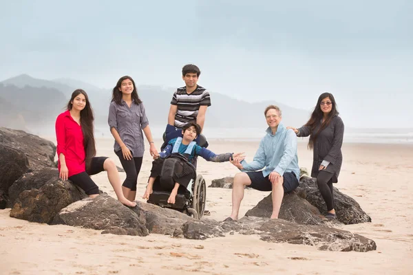 Multirassische Sonderbedürfnisse Familie sitzt auf großen Felsen entlang sein — Stockfoto
