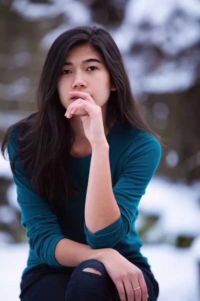 Biracial tiener meisje zittend op ontlasting buitenshuis in de winter — Stockfoto