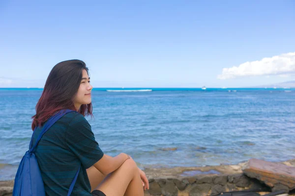 一个年轻的亚洲女孩独自坐在夏威夷海洋边 一边看着水一边休息 — 图库照片