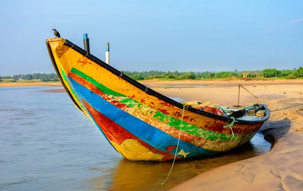 Traditional colorful fishing boat anchored at the confluence of river Mahendra Tanaya and Bay of Bengal sea