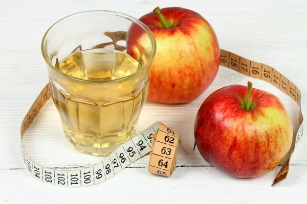 Apple vinegar good for diet. Fersh apples, measuring tape and glass on white wooden table