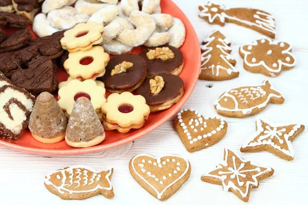 红色盘子上的圣诞糖果 圣诞糖果在白色木板和姜饼周围 — 图库照片