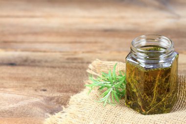 Taze bitkisel cilt bakımı kozmetik. Bitkisel yağ taze biberiye ile çuval bezi ve kahverengi ahşap tahta üzerinde yapraklar