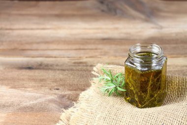 Taze bitkisel cilt bakımı kozmetik. Bitkisel yağ taze biberiye ile çuval bezi ve kahverengi ahşap tahta üzerinde yapraklar