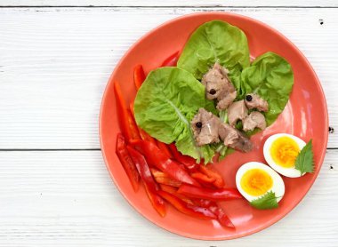 Marul yapraklarında morina ciğeri, beyaz ahşap masa, düz yatak. Morina ciğeri, haşlanmış yumurta ve tabakta kırmızı biber, sağlıklı yemek.. 