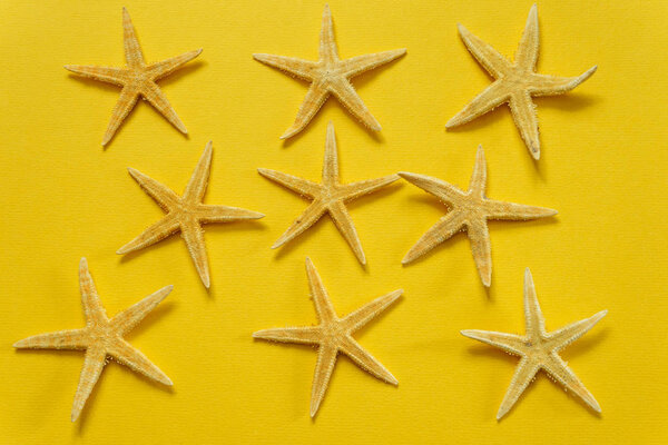 Summer background of yellow paper with starfish, symbolizing the sand on the sea coast