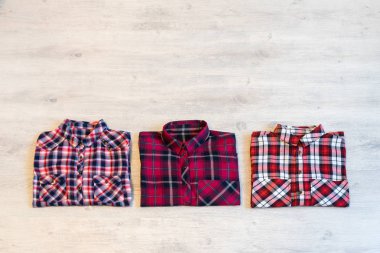 Çok renkli ve damalı üç kadın gömlek bir ışık ahşap arka plan üzerine düzgünce katlanmış yalan