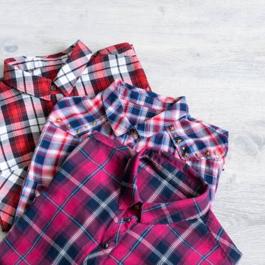 Çok renkli ve damalı üç kadın gömlek bir ışık ahşap arka plan üzerine düzgünce katlanmış yalan