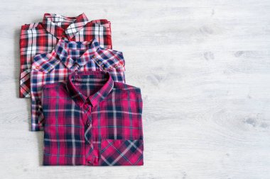 Çok renkli ve damalı üç kadın gömlek bir ışık ahşap arka plan üzerine düzgünce katlanmış yalan