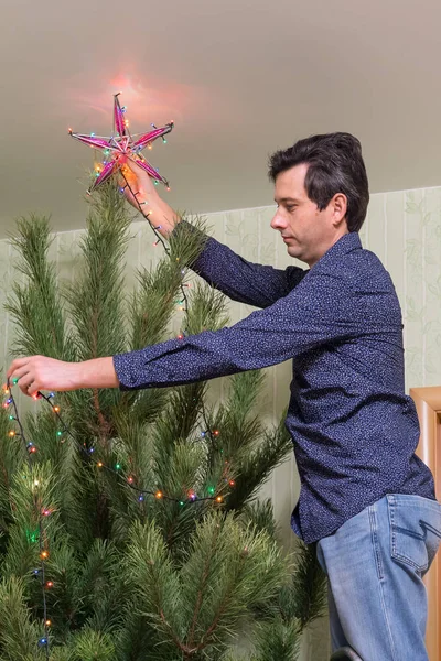 Hombre Guapo Mediana Edad Decora Árbol Navidad Con Una Estrella — Foto de Stock