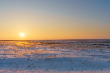 Kış manzara karla kaplı düz, mavi gökyüzü ve gün batımı turuncu güneşe. Güzel doğal manzaralı arka plan
