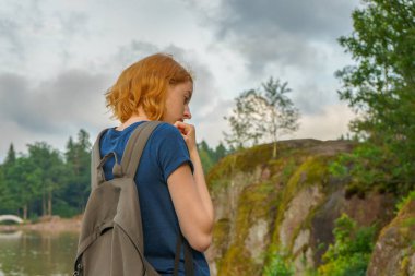 Genç güzel Bayan sırt çantası açık havada yaz akşamları yürüyüş ile. Güzel manzara arka plan üzerinde turist. Monrepos Park, Vyborg, Rusya Federasyonu. Seyahat kavramı