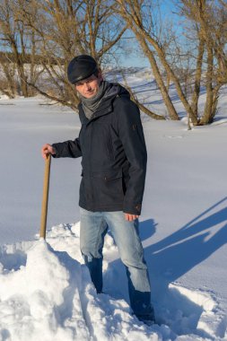 Yakışıklı orta yaşlı beyaz adam kar ev arsa üzerinde temizler