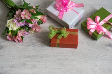 Renkli gül buketi, ahşap arka plan üzerinde hediye kutuları ile krizantem ve alstroemeria çiçekler