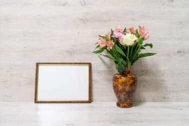 Renkli bahar buket gül, krizantem ve alstroemeria ahşap arka plan üzerinde boş photoframe ile bir vazoda
