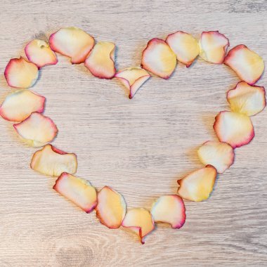 Çerçeve ışık ahşap arka plan üzerinde kalp şeklinde kurutulmuş krem gül yaprakları. Aşk, romantizm ya da Sevgililer günü kavramı, alay etmek yukarıya. Yat, uzay, üstten görünüm Kopyala