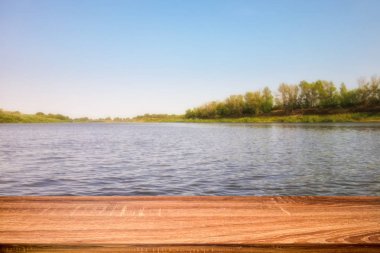 Yaz arka planını gündüz nehir kenarında boş ahşap masa. Görüntü veya montaj ürünleri için kullanılabilir