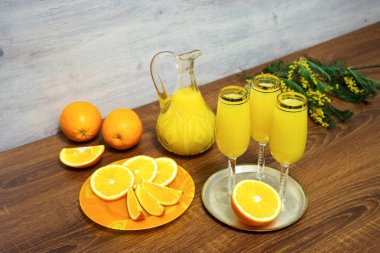 Mimoza kokteyli, portakal suyu, taze portakal ve Mimoza fışkın ahşap bir masa üzerinde bir sürahi üç bardak