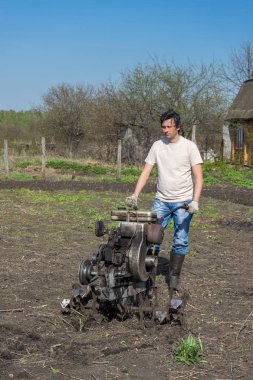 Adam Kültüvatör ile zemin pulluklar. Ekimi toprak, toprak işleme toprak. Bahçe, Bahar adet eser bulunmaktadır. Bahçe kavramı.