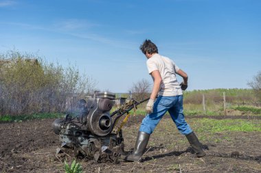 Adam Kültüvatör ile zemin pulluklar. Ekimi toprak, toprak işleme toprak. Bahçe, Bahar adet eser bulunmaktadır. Bahçe kavramı.