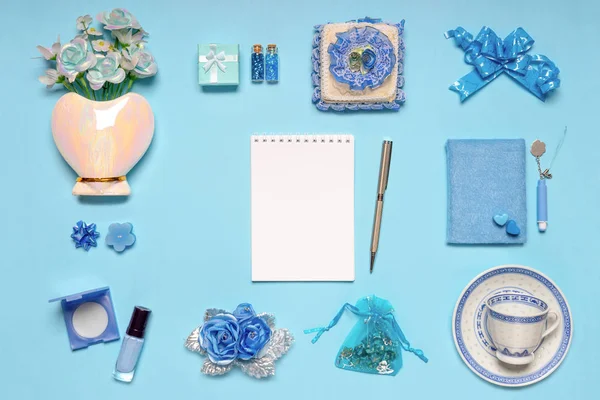 Κομψά γυναικεία αξεσουάρ, λουλούδια, καλλυντικά, δώρα και διακοσμητικά αντικείμενα με μπλε παστέλ χρώματα σε μπλε φόντο. Κενή σελίδα σημειωματάριων, χλευάσουμε επάνω. Γυναικεία ή της μητέρας ημέρα έννοια. Επίπεδη θέσει — Φωτογραφία Αρχείου