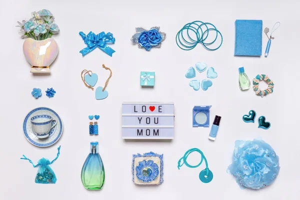 Stilvolle feminine Accessoires, Blumen, Kosmetik, Schmuck, Parfüm in blauen Pastellfarben auf weißem Hintergrund. Text love you mom on ligthbox, Grußkarte zum Muttertag — Stockfoto