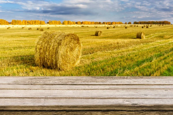 Empty wooden table with blurred autumn landscape of beveled field and straw bales. Mock up for display or montage products — Stock Photo, Image