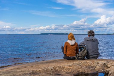 Turistler adam ve kadın yaz gününde Kuzey göl kıyısında oturuyor. İnsanlar rahatlatıcı ve güzel manzara hayran. Dünya 'nın uzak yerlerini keşfetmek ve seyahat etmek. Onega Lake, Karelia, Rusya Federasyonu