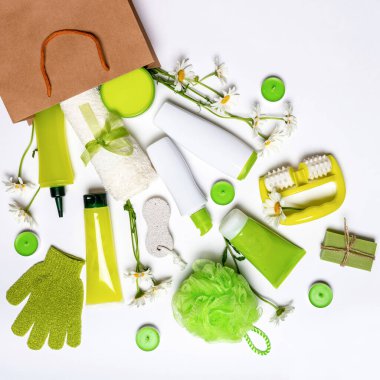 Şık şişelerde vücut bakımı kozmetik ürünleri masaj malzemeleri ve papatya çiçekleri ve beyaz arka planda mumlarla kraft çantasının içinde soyulmak. Bahar güncellemesi, kaplıca ve güzellik konsepti.