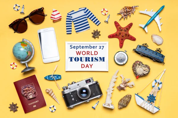 Happy world tourism day. Touristic objects, smartphone, passport, camera, sunglasses and decorative items on light background. Flat lay, top view. Photoframe, text September 27 WORLD TOURISM DAY