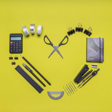 Açık yeşil arka planda siyah ve gri kırtasiyeden yapılmış kalp sembolü. Ofis malzemeleri, defter, hesap makinesi, makas. Eğitim ve iş konsepti. Düz konum, üst görünüm, kopyalama alanı.