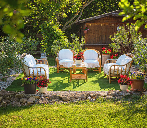 Уютные садовые шезлонги с подушками, в окружении цветов
