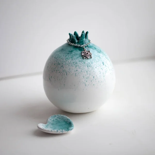 Vit keramik granat äpple med turkos fläckar på ett vitt bord — Stockfoto