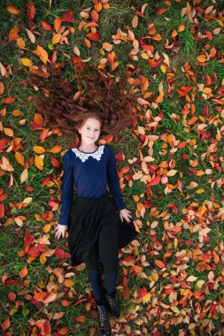 Dans ve renkli yaprakları Bahçe sonbahar dolu oynayan kırmızı saçlı kız.