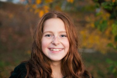 Dans ve renkli yaprakları Bahçe sonbahar dolu oynayan kırmızı saçlı kız.