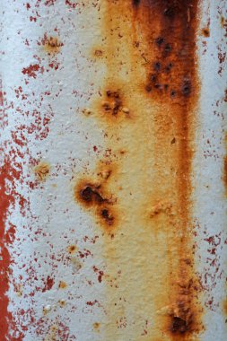 Beyaz ve kırmızı boyalı paslı metal bir yüzeyin yakından, dikey ve soyut görüntüsü desen ve renklerin bir karışımını sergiliyor.